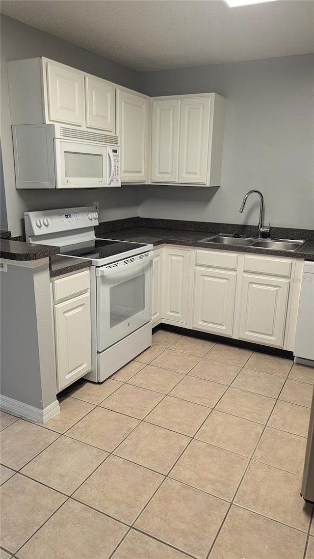 kitchen featuring sink, white appliances, light tile patterned floors, and white cabinetry