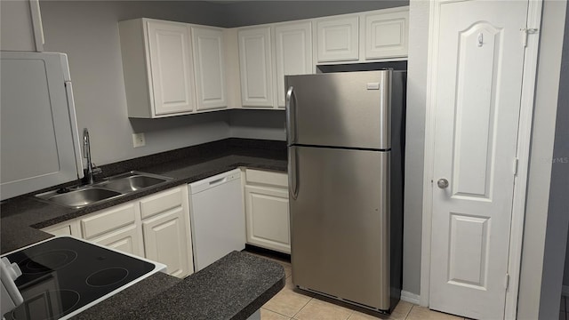 kitchen featuring stainless steel fridge, light tile patterned flooring, dishwasher, and white cabinets