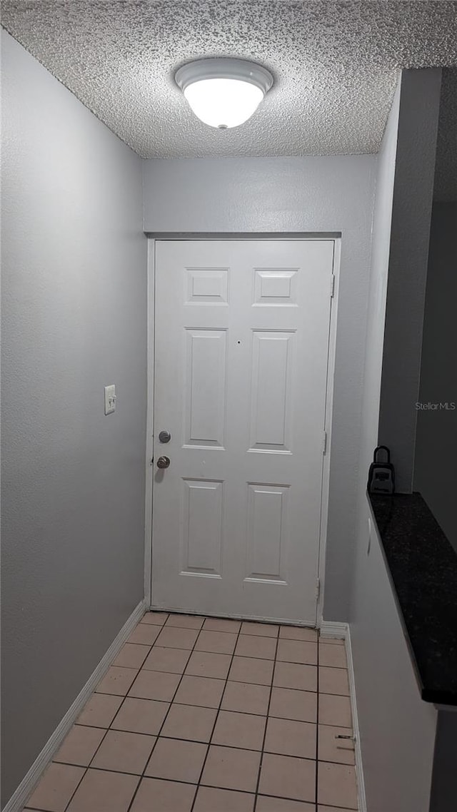 entryway with light tile patterned flooring and a textured ceiling