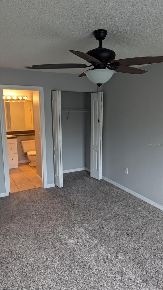 unfurnished bedroom with a closet, ceiling fan, carpet flooring, ensuite bathroom, and a textured ceiling