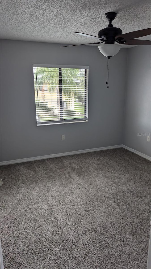 carpeted spare room with a textured ceiling, ceiling fan, and a wealth of natural light