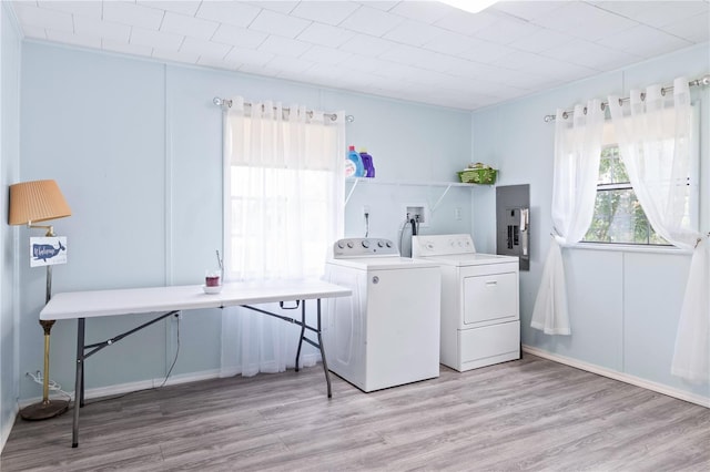 laundry room with separate washer and dryer, electric panel, and light wood-type flooring