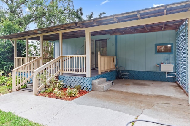 doorway to property featuring a carport, covered porch, and sink