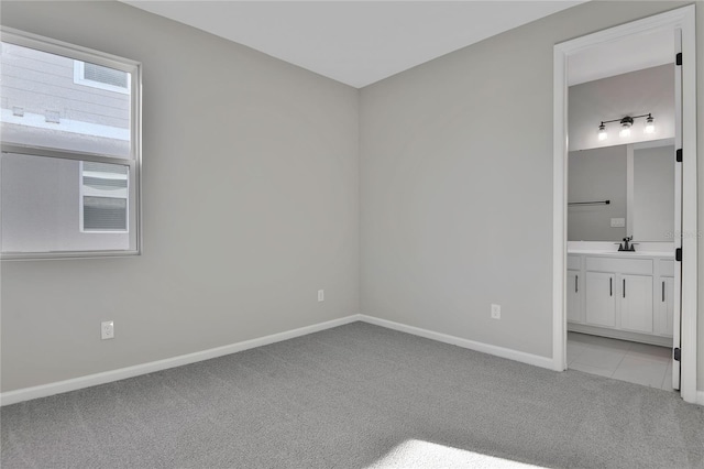 unfurnished bedroom featuring sink, connected bathroom, and light colored carpet