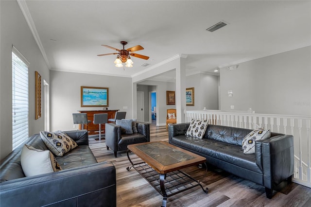 living room with hardwood / wood-style flooring, ornamental molding, and ceiling fan