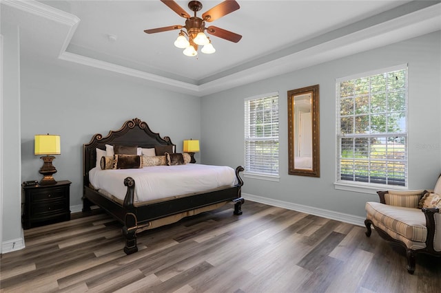 bedroom with dark hardwood / wood-style floors, a raised ceiling, and ceiling fan