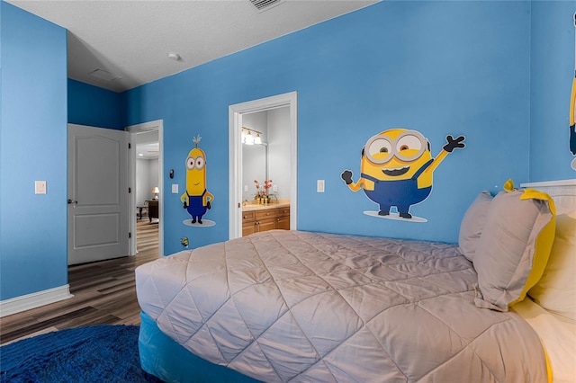 bedroom featuring hardwood / wood-style floors, a textured ceiling, and ensuite bath