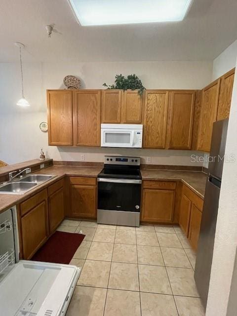 kitchen featuring sink, stainless steel range with electric stovetop, light tile patterned floors, and refrigerator