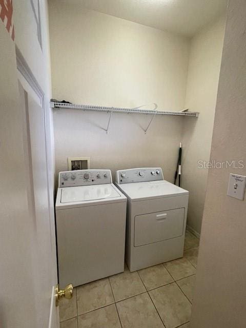 clothes washing area featuring washer and dryer and light tile patterned floors