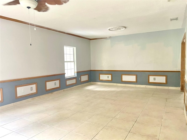 tiled spare room featuring ceiling fan and crown molding