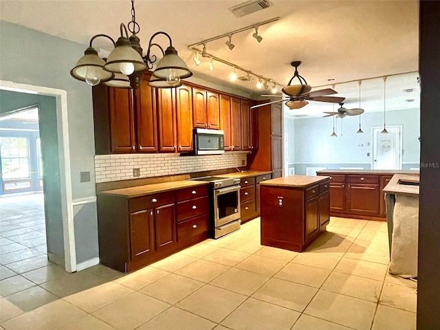 kitchen featuring stainless steel appliances, a center island, light tile patterned floors, decorative backsplash, and ceiling fan with notable chandelier