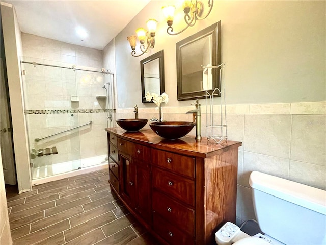 bathroom with toilet, an enclosed shower, tile walls, and vanity