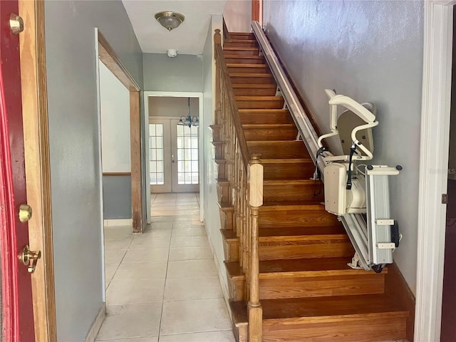 staircase featuring french doors, a chandelier, and tile patterned floors