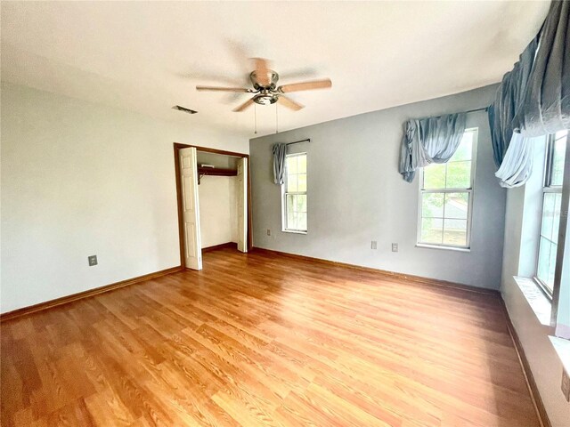 unfurnished bedroom featuring multiple windows, a closet, ceiling fan, and light hardwood / wood-style flooring