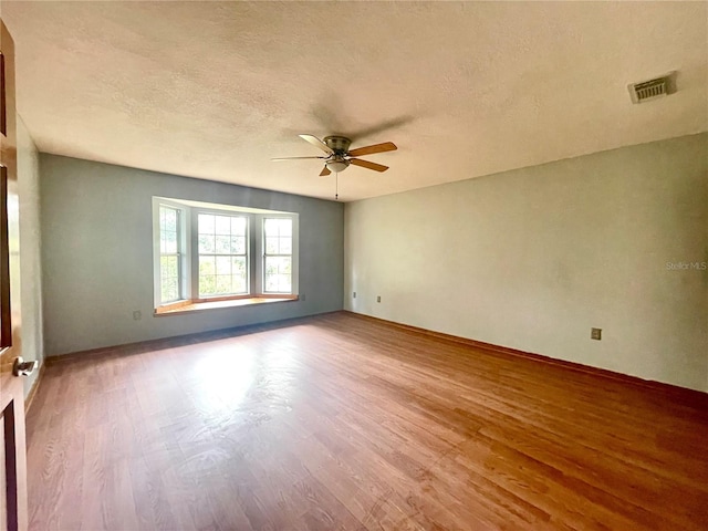 unfurnished room with a textured ceiling, ceiling fan, and wood-type flooring