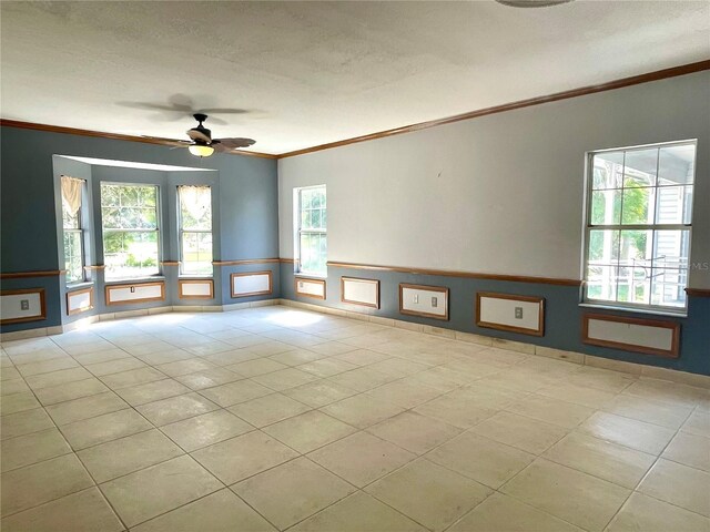 tiled empty room with ceiling fan, ornamental molding, and a textured ceiling