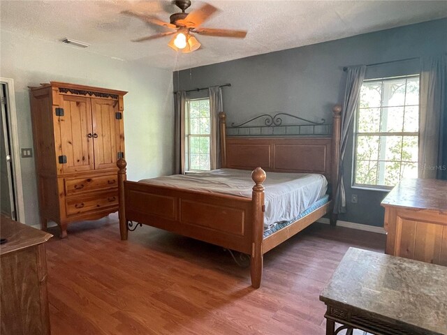 bedroom featuring a textured ceiling, ceiling fan, and dark hardwood / wood-style flooring