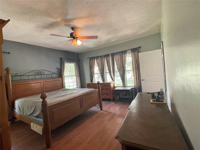 bedroom with ceiling fan, a textured ceiling, and dark hardwood / wood-style floors