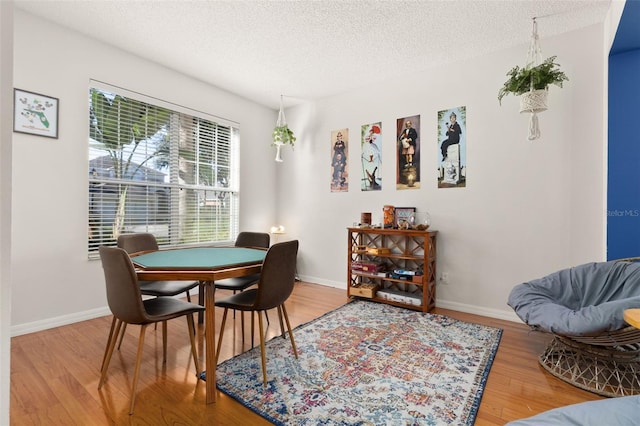 dining room featuring wood-type flooring and a textured ceiling