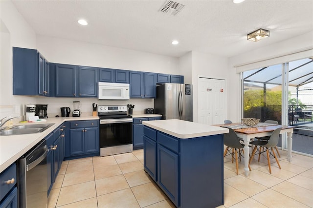 kitchen with light tile patterned flooring, sink, blue cabinets, and stainless steel appliances