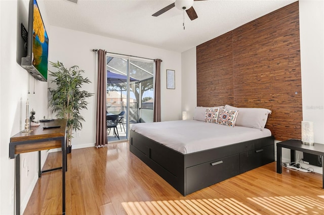 bedroom with access to exterior, ceiling fan, light hardwood / wood-style flooring, and a textured ceiling