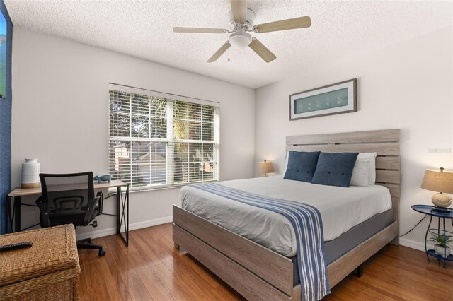 bedroom with hardwood / wood-style flooring, ceiling fan, and a textured ceiling