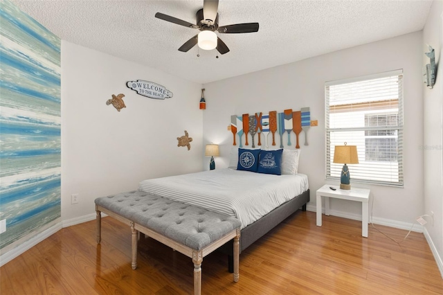 bedroom with a textured ceiling, light hardwood / wood-style flooring, and ceiling fan