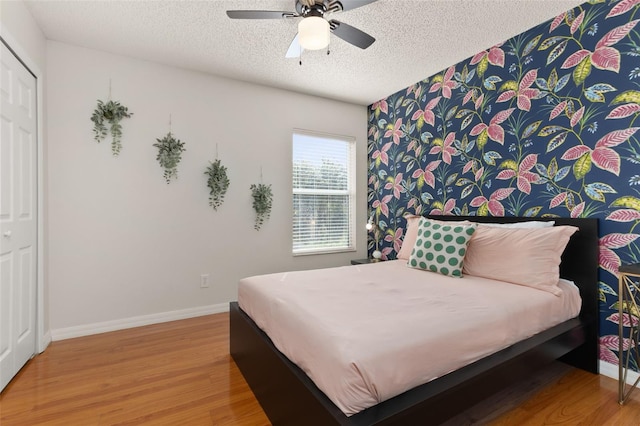 bedroom featuring wood-type flooring, a textured ceiling, a closet, and ceiling fan