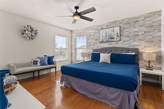 bedroom with hardwood / wood-style flooring, ceiling fan, and a textured ceiling