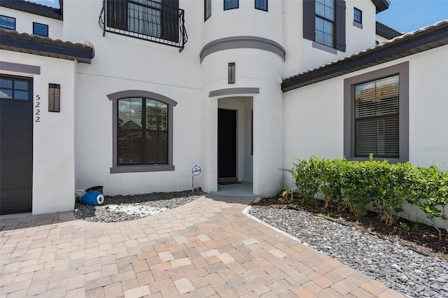 view of exterior entry featuring a tiled roof and stucco siding