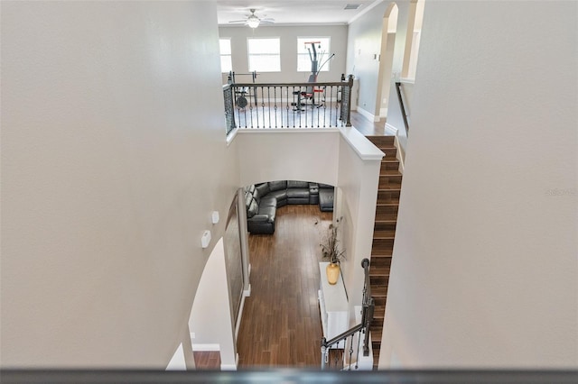 stairway featuring wood finished floors, baseboards, and ceiling fan