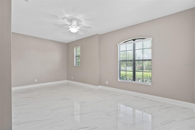 spare room with baseboards, marble finish floor, and a ceiling fan