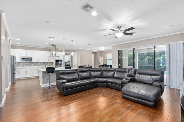 living room featuring a textured ceiling, ceiling fan, and crown molding