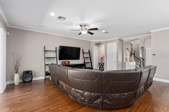 living area with arched walkways, visible vents, baseboards, and wood finished floors