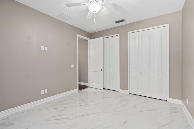 unfurnished bedroom featuring visible vents, marble finish floor, two closets, and baseboards