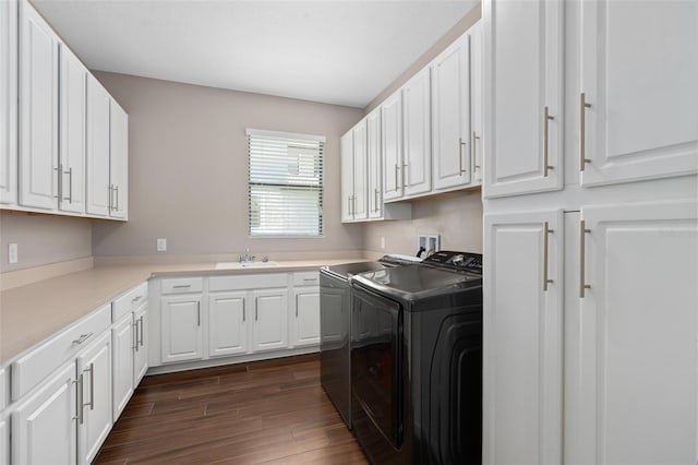 clothes washing area with sink, washer and dryer, cabinets, and dark wood-type flooring