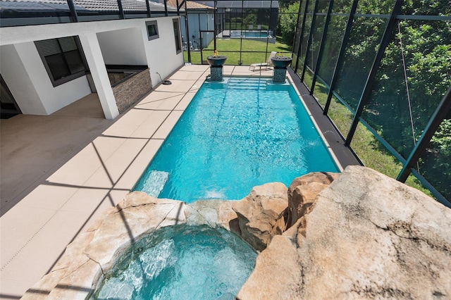 outdoor pool with glass enclosure, an in ground hot tub, and a patio