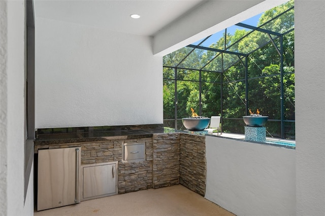 view of patio featuring glass enclosure and area for grilling