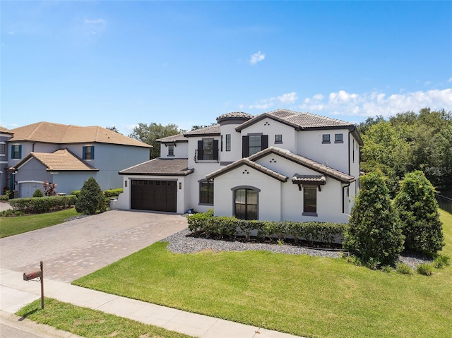 mediterranean / spanish house with stucco siding, a tile roof, decorative driveway, an attached garage, and a front yard