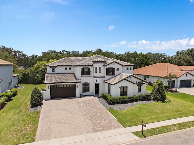 view of front of home featuring decorative driveway, a front lawn, a tiled roof, and an attached garage