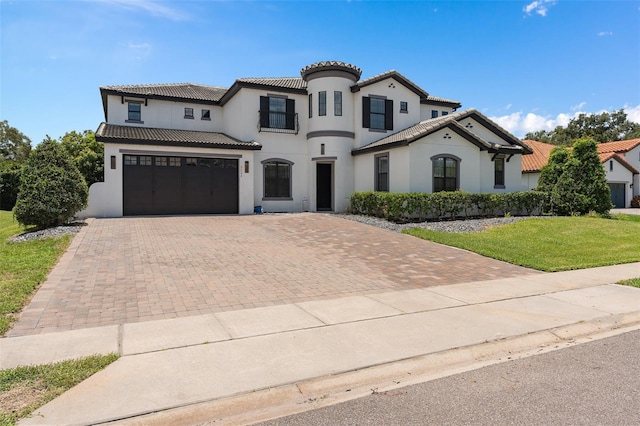 mediterranean / spanish-style house featuring a front yard, decorative driveway, a tile roof, and an attached garage