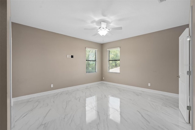 spare room featuring marble finish floor, a ceiling fan, and baseboards