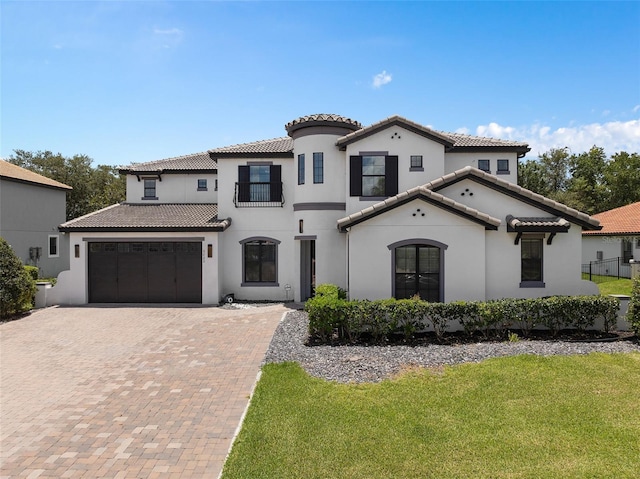 mediterranean / spanish-style home featuring a tiled roof, decorative driveway, a garage, and stucco siding