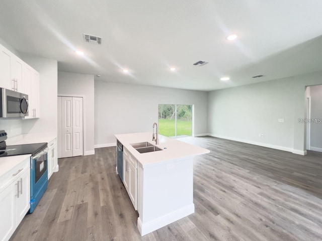 kitchen featuring stainless steel appliances, hardwood / wood-style floors, white cabinets, sink, and a kitchen island with sink