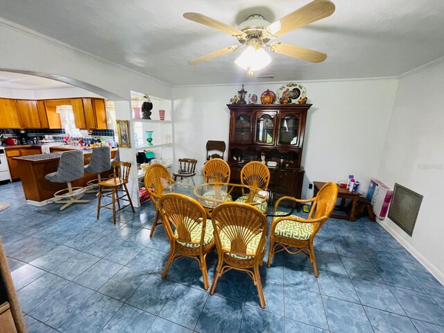 dining space featuring ceiling fan, dark tile patterned flooring, and ornamental molding