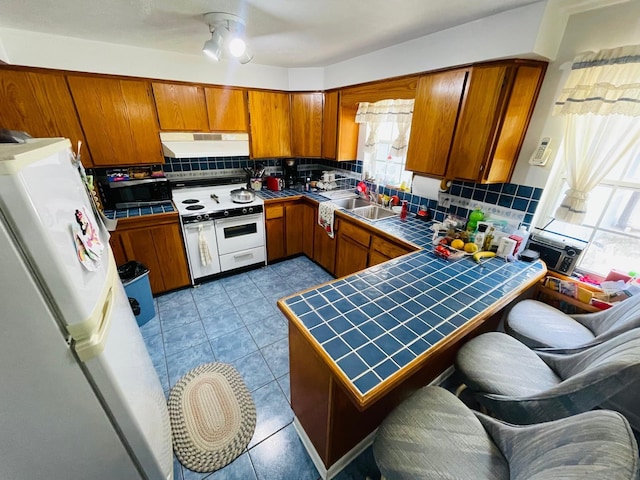 kitchen featuring backsplash, white appliances, sink, and tile countertops