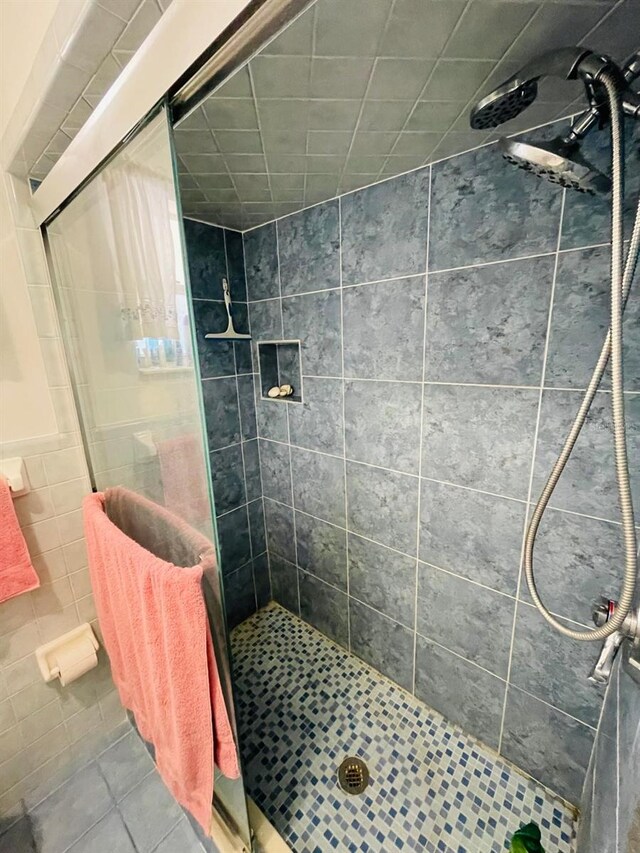 bathroom featuring walk in shower, tile walls, and tile patterned floors