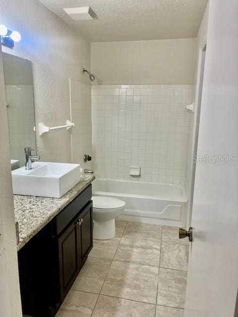 full bathroom with toilet, tile patterned flooring, vanity, a textured ceiling, and tiled shower / bath combo