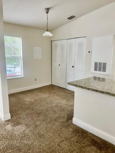 unfurnished bedroom with lofted ceiling, dark carpet, and a closet