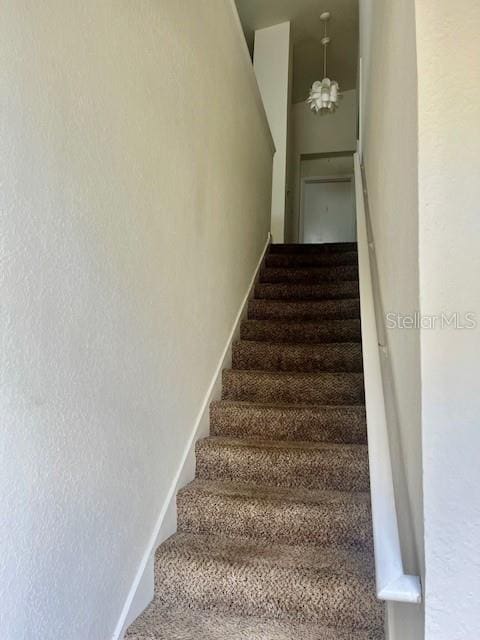 stairway featuring a chandelier